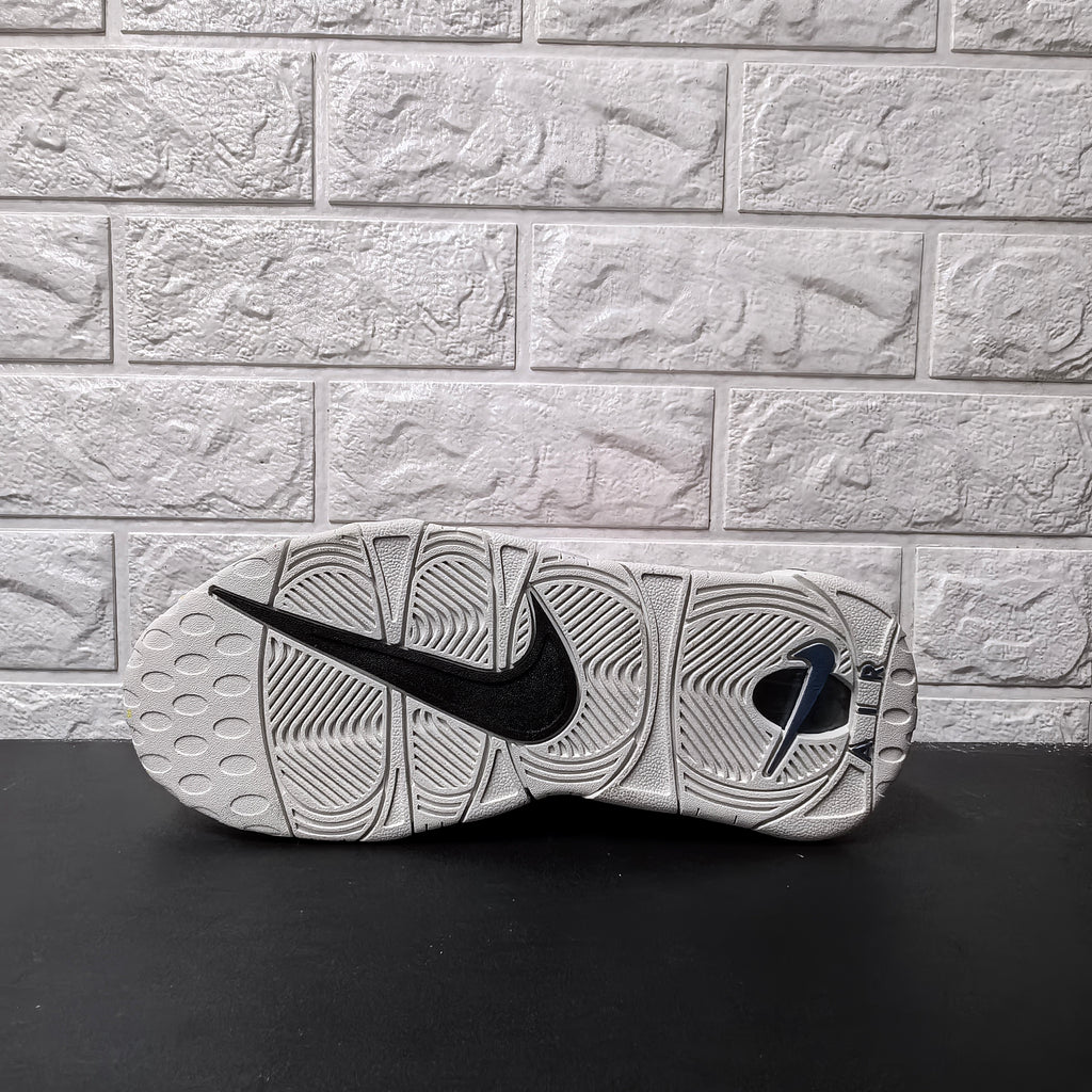 Underside of grey sneaker showing patterned outsole and black Nike Swoosh