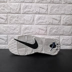 Underside of grey sneaker showing patterned outsole and black Nike Swoosh