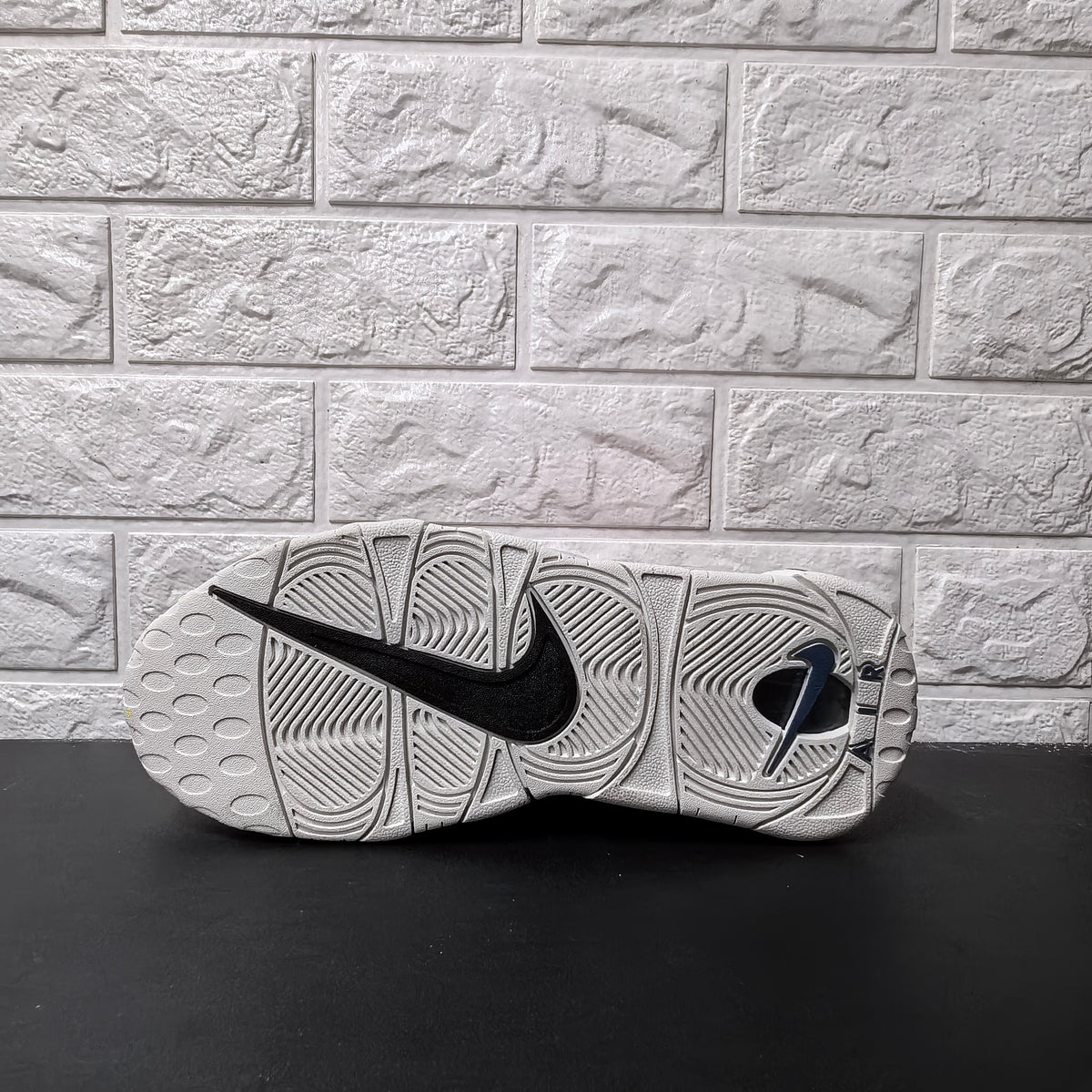 Underside of grey sneaker showing patterned outsole and black Nike Swoosh