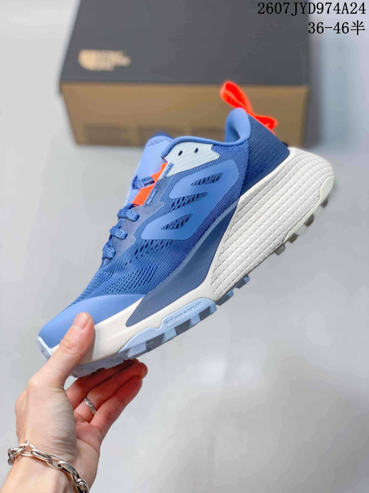 Side profile showing the blue mesh-style upper, layered overlays, orange details, and lugged outsole.