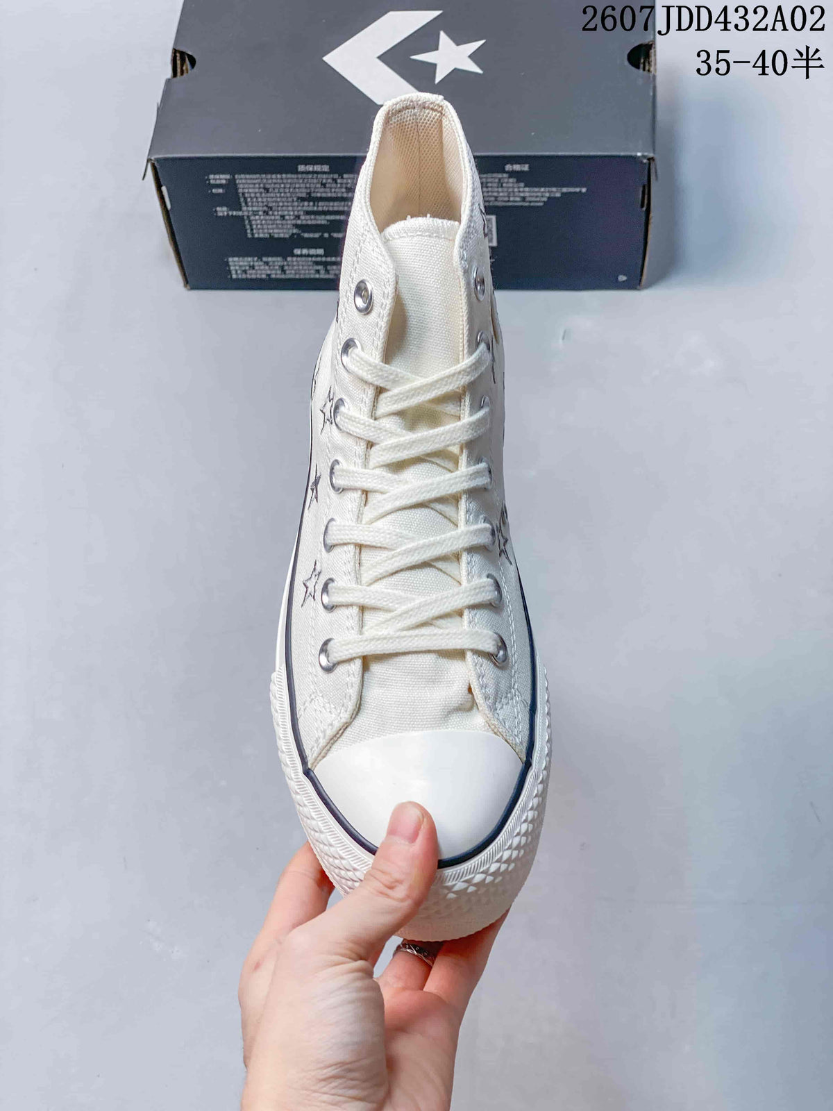 Front view of the cream high-top sneaker with white laces, metal eyelets, and rubber toe cap.
