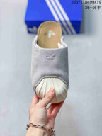 Front view of the grey mule slide showing the embroidered upper mark and ribbed white toe covering.