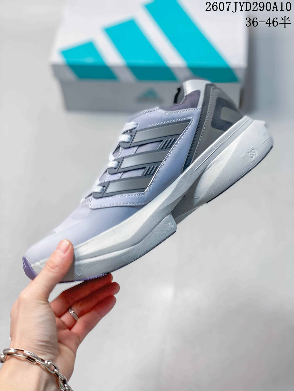 Side view of the gray and light purple adidas shoe showing layered side panels, lace construction and a raised white midsole.