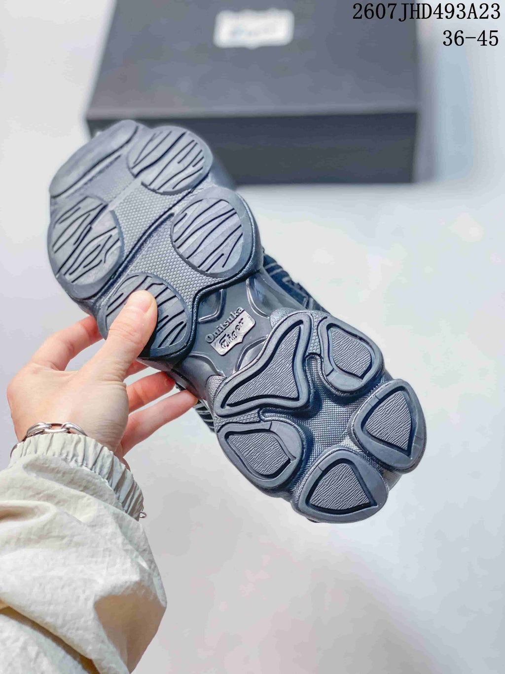 Underside of a dark Onitsuka Tiger sneaker showing the segmented sculpted outsole tread.