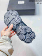 Underside of a dark Onitsuka Tiger sneaker showing the segmented sculpted outsole tread.