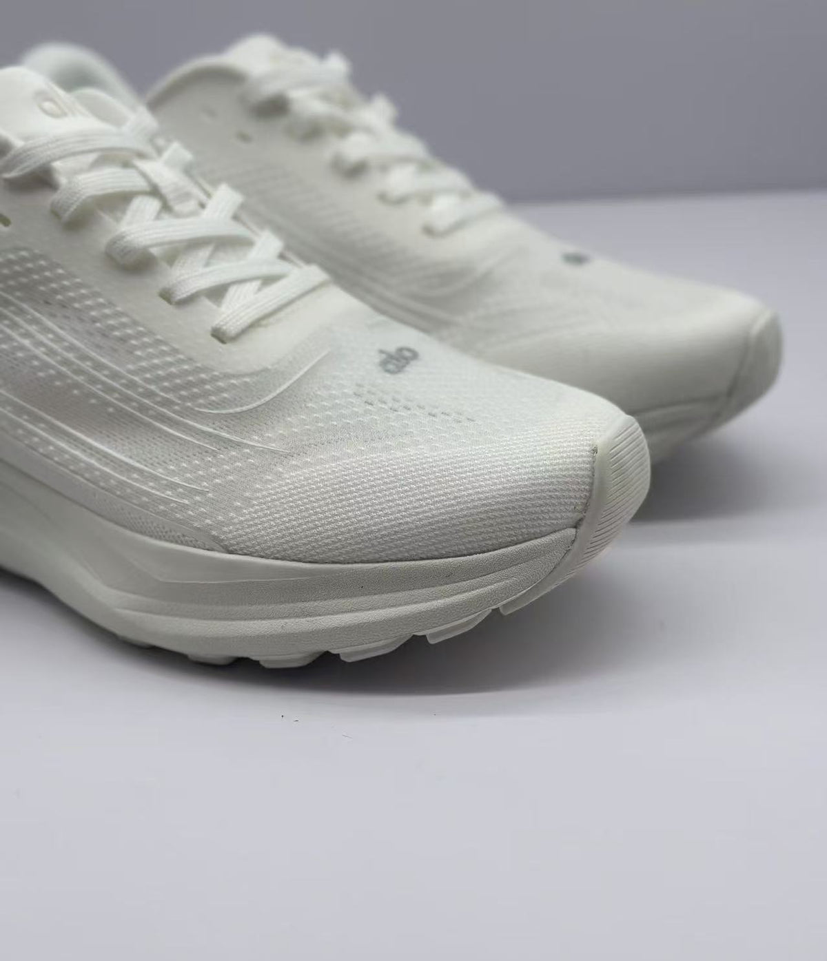 Close-up of the white sneaker toe box, laces, textured upper, and layered midsole.