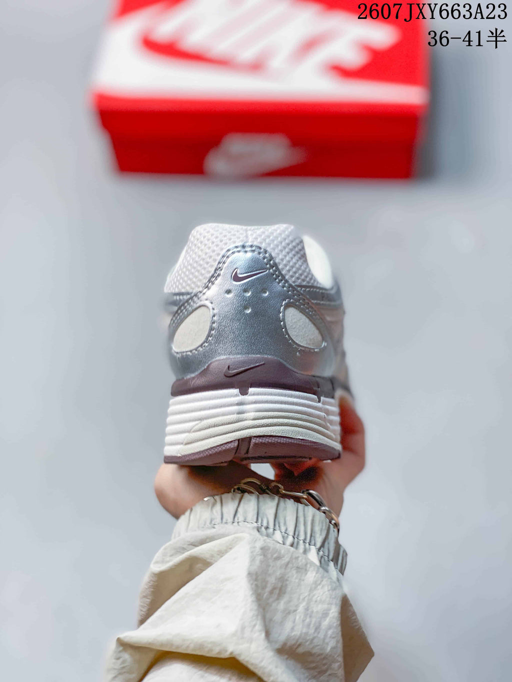 Rear view of the white and silver sneaker showing the heel overlay and textured midsole.