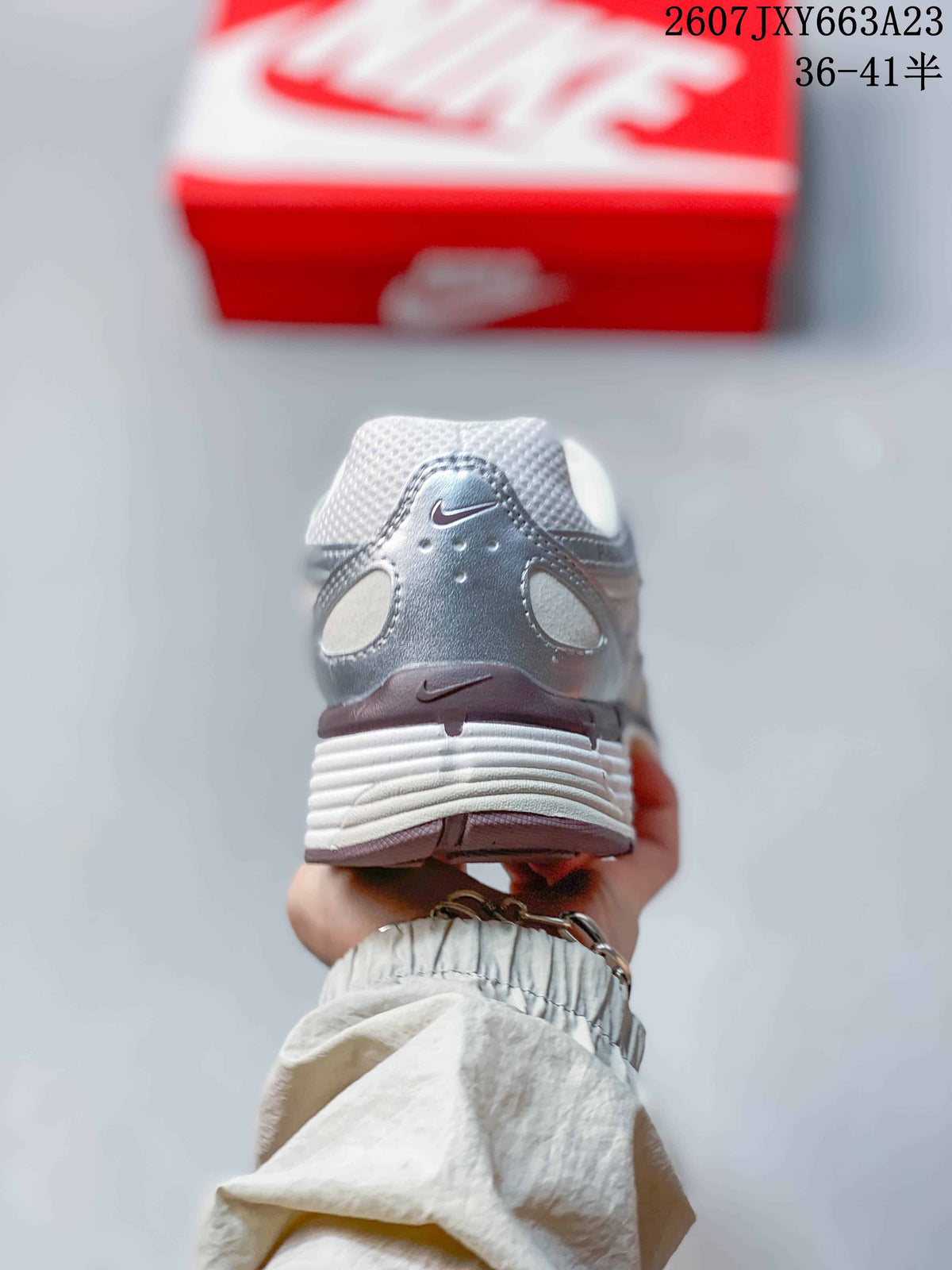 Rear view of the white and silver sneaker showing the heel overlay and textured midsole.