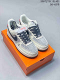 Pair of cream and gray low-top sneakers with patterned panels and dark laces, placed on an orange box.