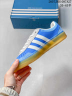 Side view showing the blue upper, white three stripes, textured overlays, and gum outsole.