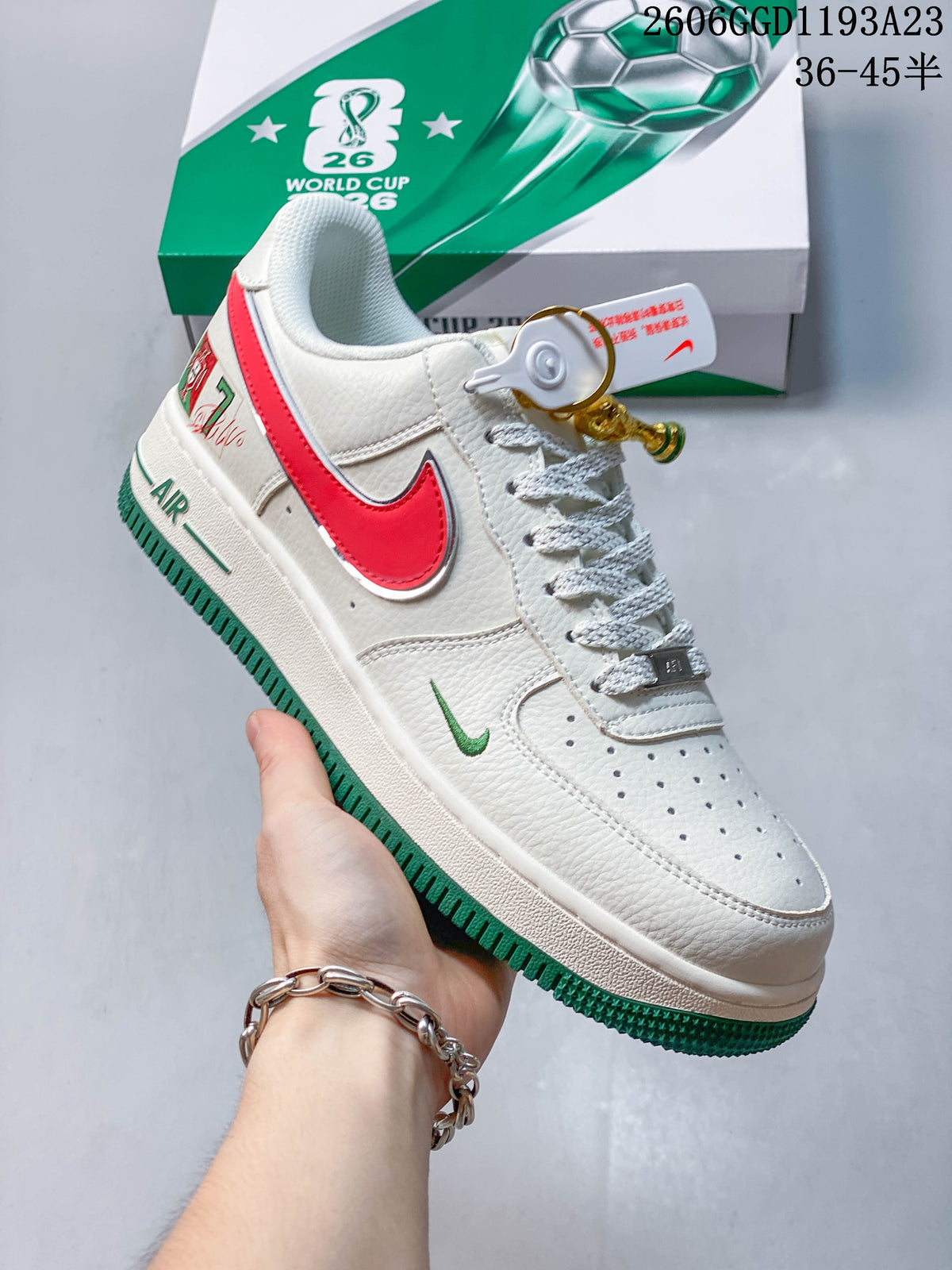 Angled side view of the white sneaker with red side accent, green details, and trophy-shaped charm.