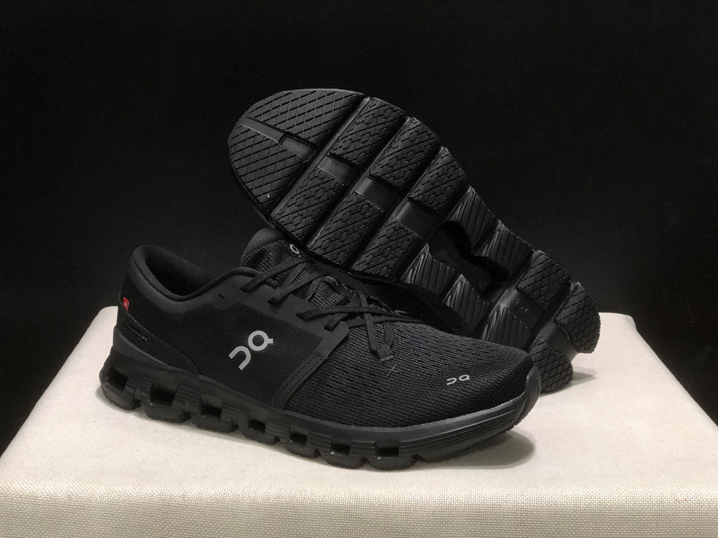 Black On Cloud X4 shoe shown with the outsole facing upward, displaying its segmented tread pattern.