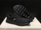 Black On Cloud X4 shoe shown with the outsole facing upward, displaying its segmented tread pattern.