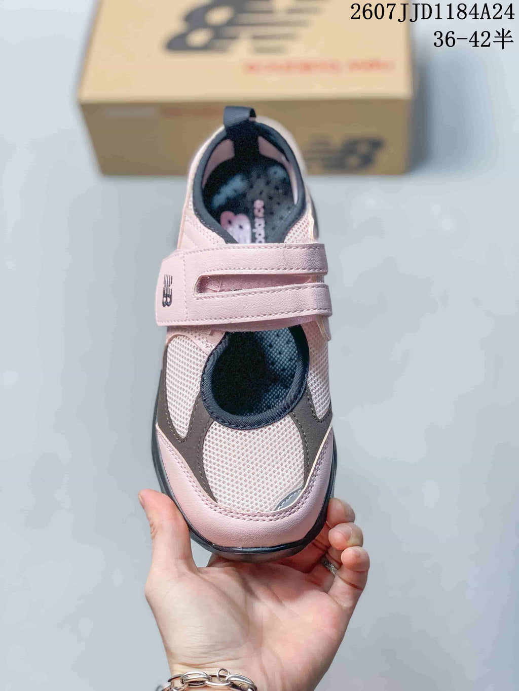 Top view of one sneaker showing the adjustable strap, mesh toe area, dark trim, and pink upper.