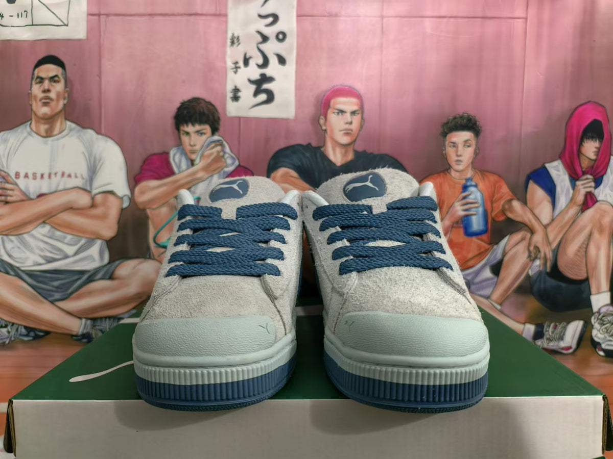 Front view of gray and blue low-top Puma sneakers with dark blue laces