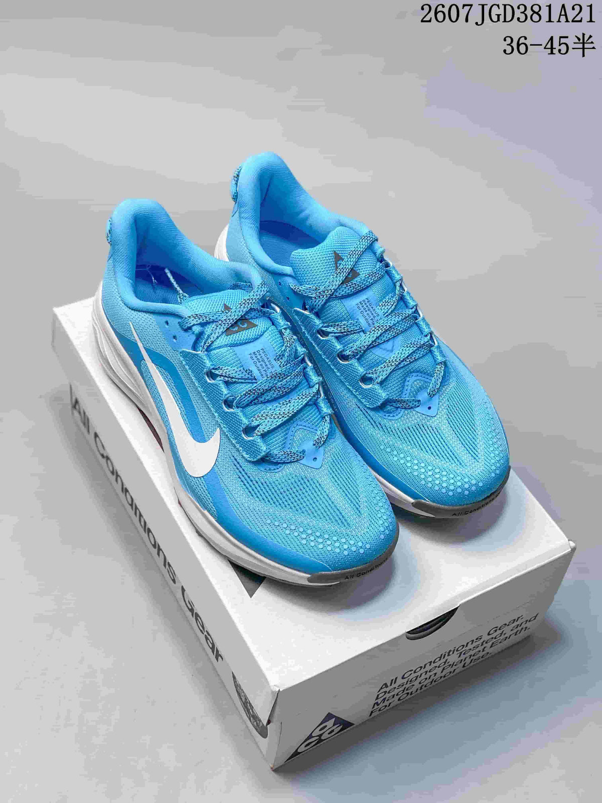 Blue Nike ACG Pegasus Trail sneakers displayed on an ACG shoebox, showing the lace-up upper, white Swoosh, and white midsole.