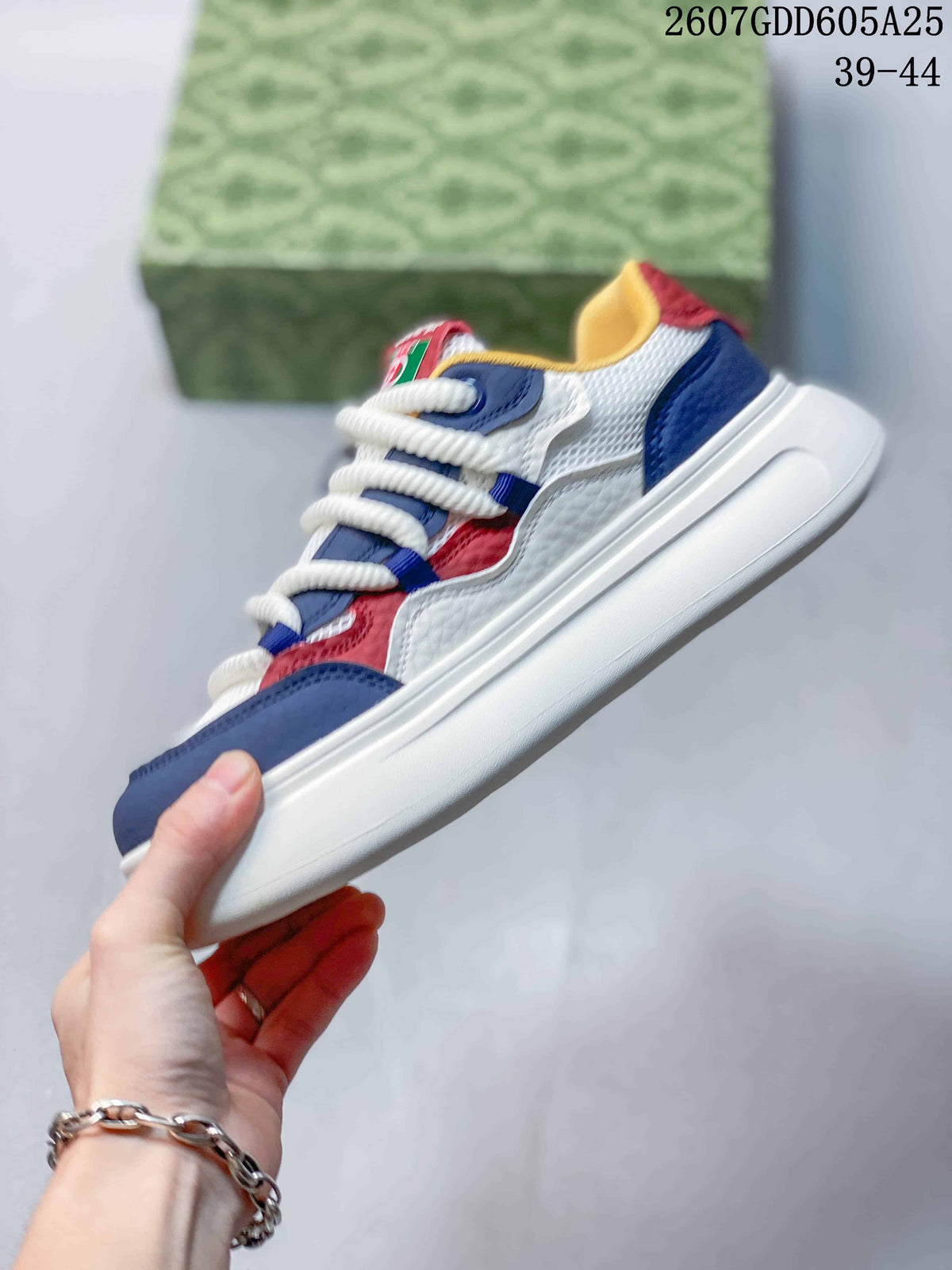 Side profile showing the low-top sneaker, white thick sole, navy and red overlays, and white mesh-look panels.