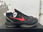 Side view of a Nike Kobe shoe with a red Swoosh, dark camouflage upper, and gray outsole.