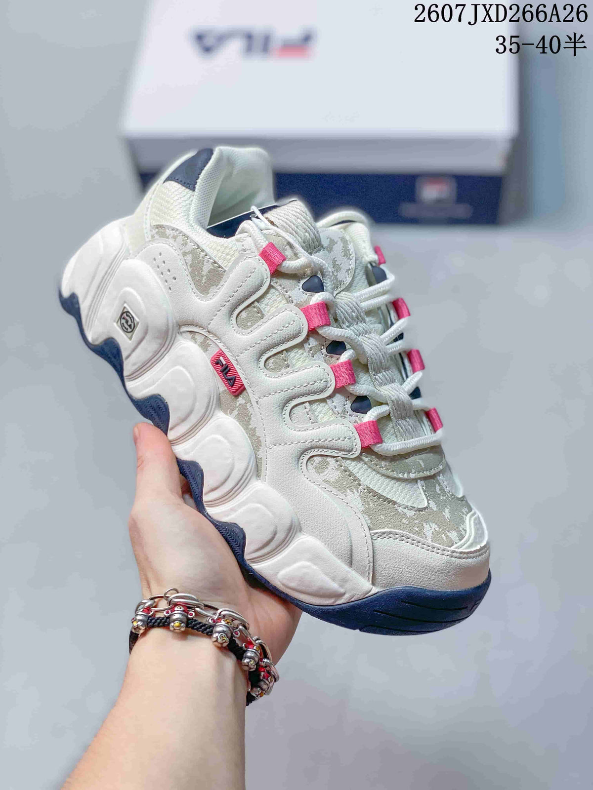 Angled side view of the FILA Croissant sneaker showing its layered upper, pink lace accents, white sculpted sole, and dark blue outsole.