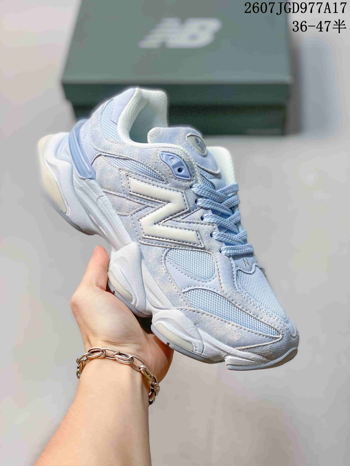 Angled side view of the light blue and white New Balance 9060 sneaker with layered upper details and a raised sole.