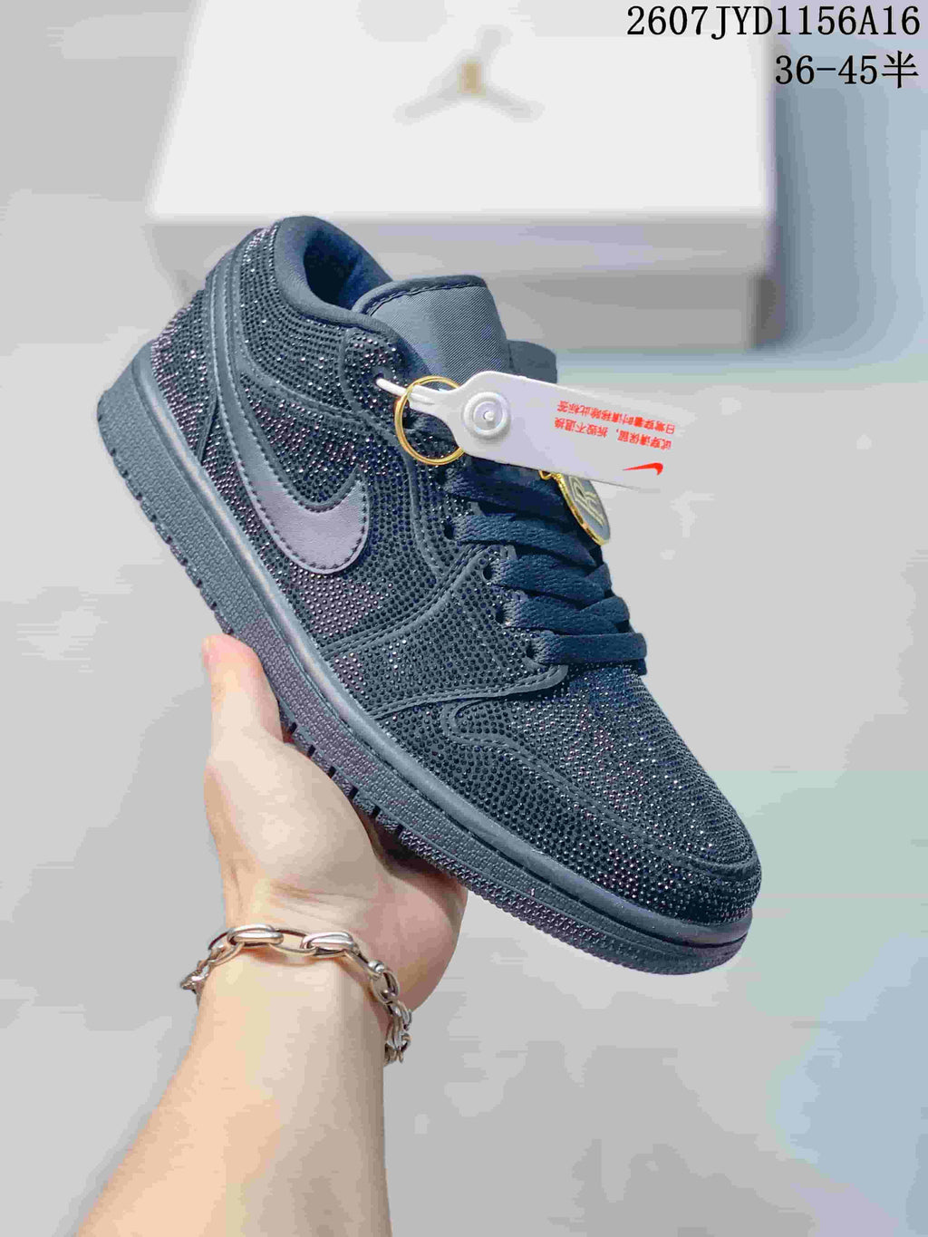 Angled side view of a black Jordan sneaker showing the reflective embellished upper, tonal Swoosh and decorative hangtags.