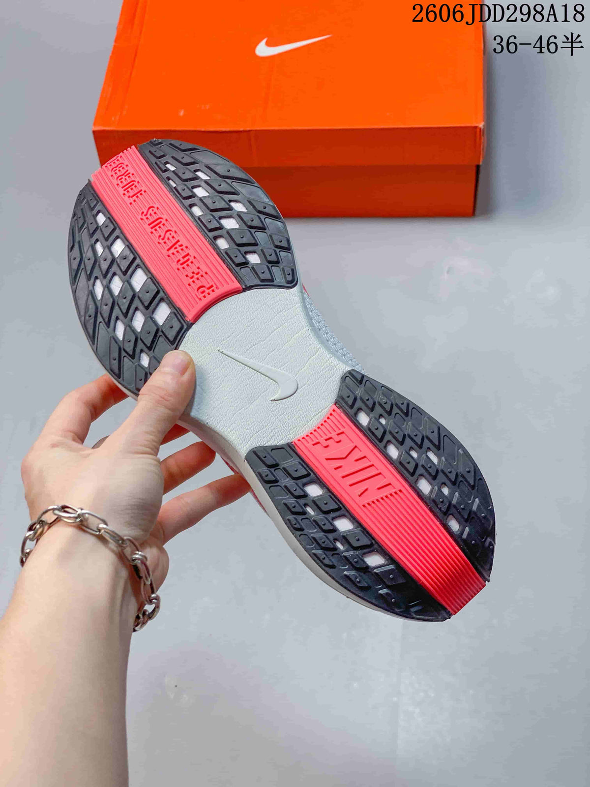 Close view of the sneaker outsole showing black tread sections, red traction panels, and a white center section.