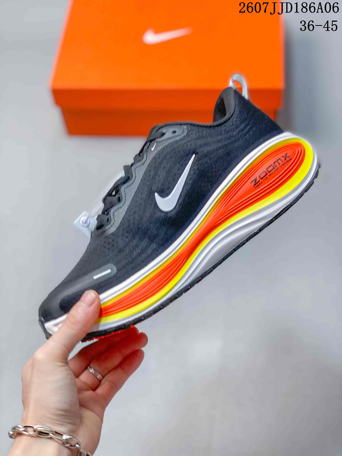 Side view of a dark Nike Vomero 18 GTX shoe showing the white swoosh, layered orange and yellow midsole, and black outsole.