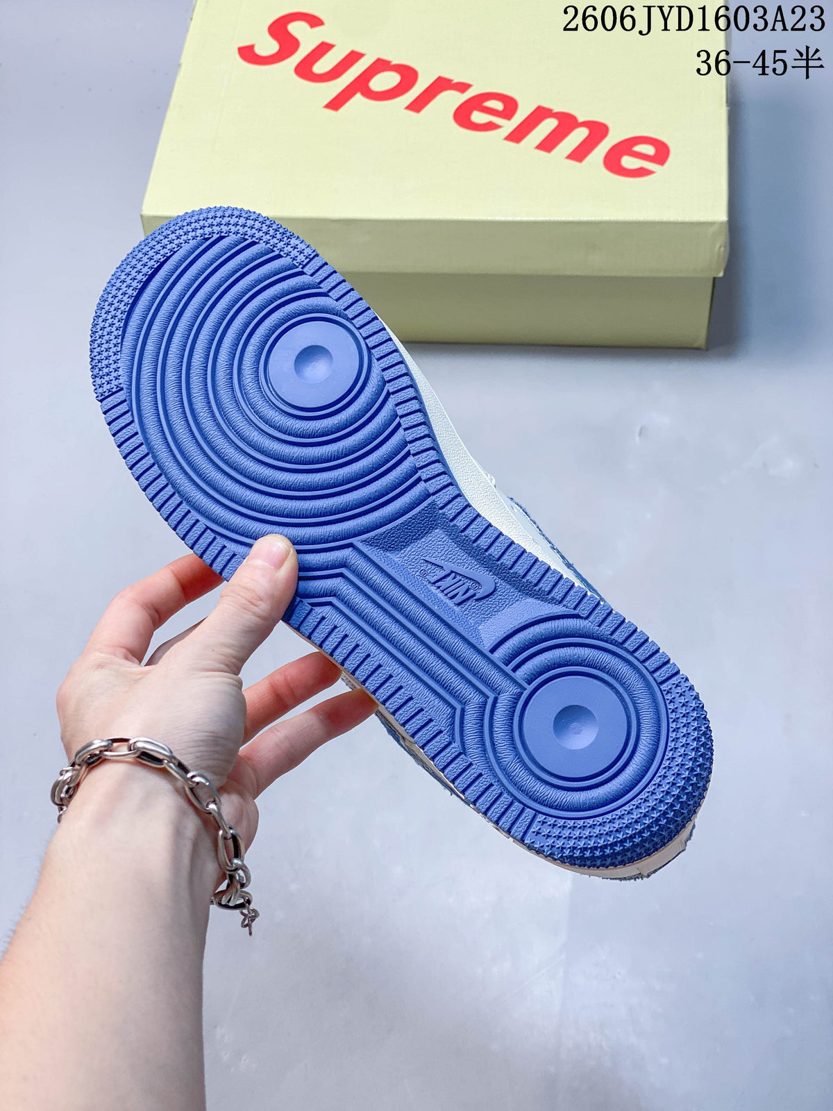 Blue outsole of the low-top sneaker, with a branded box in the background