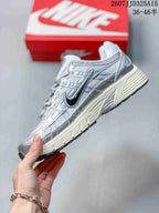 Side profile of the silver and white sneaker showing its layered panels, black Nike Swoosh, laces, and sculpted midsole.
