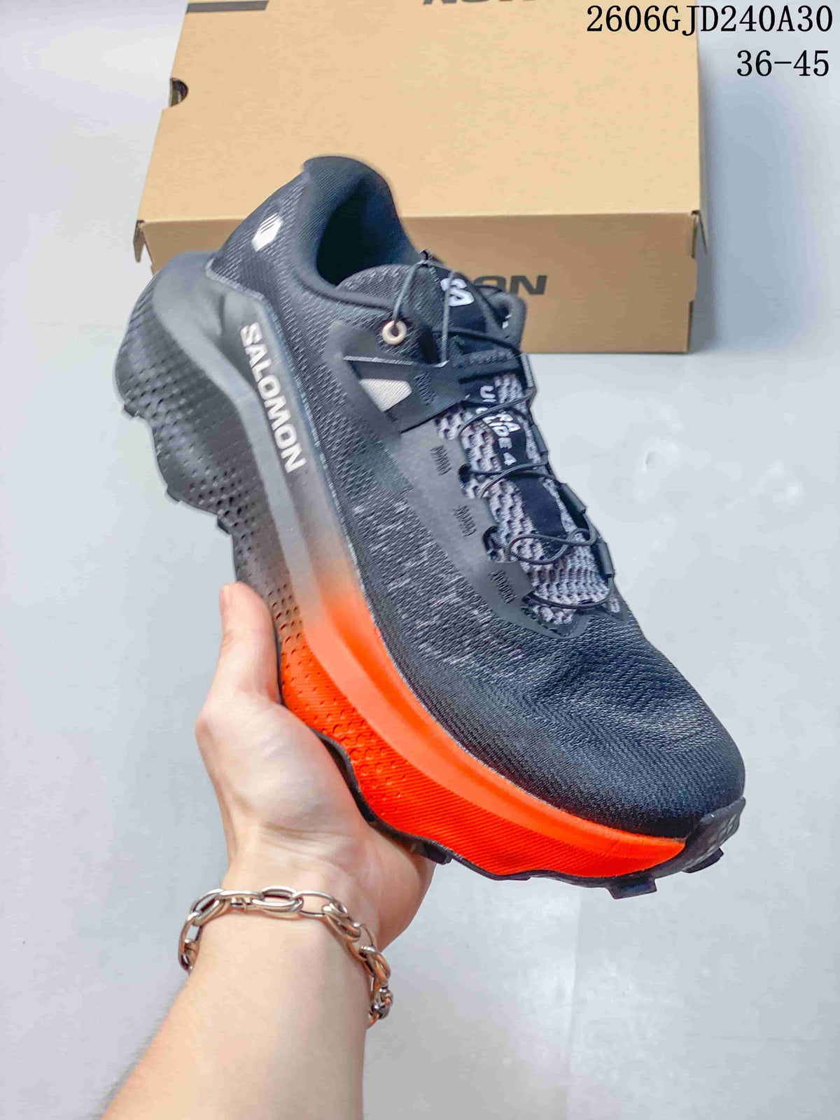 Side view of a charcoal Salomon Ultra Glide 4 shoe with a bright orange outsole