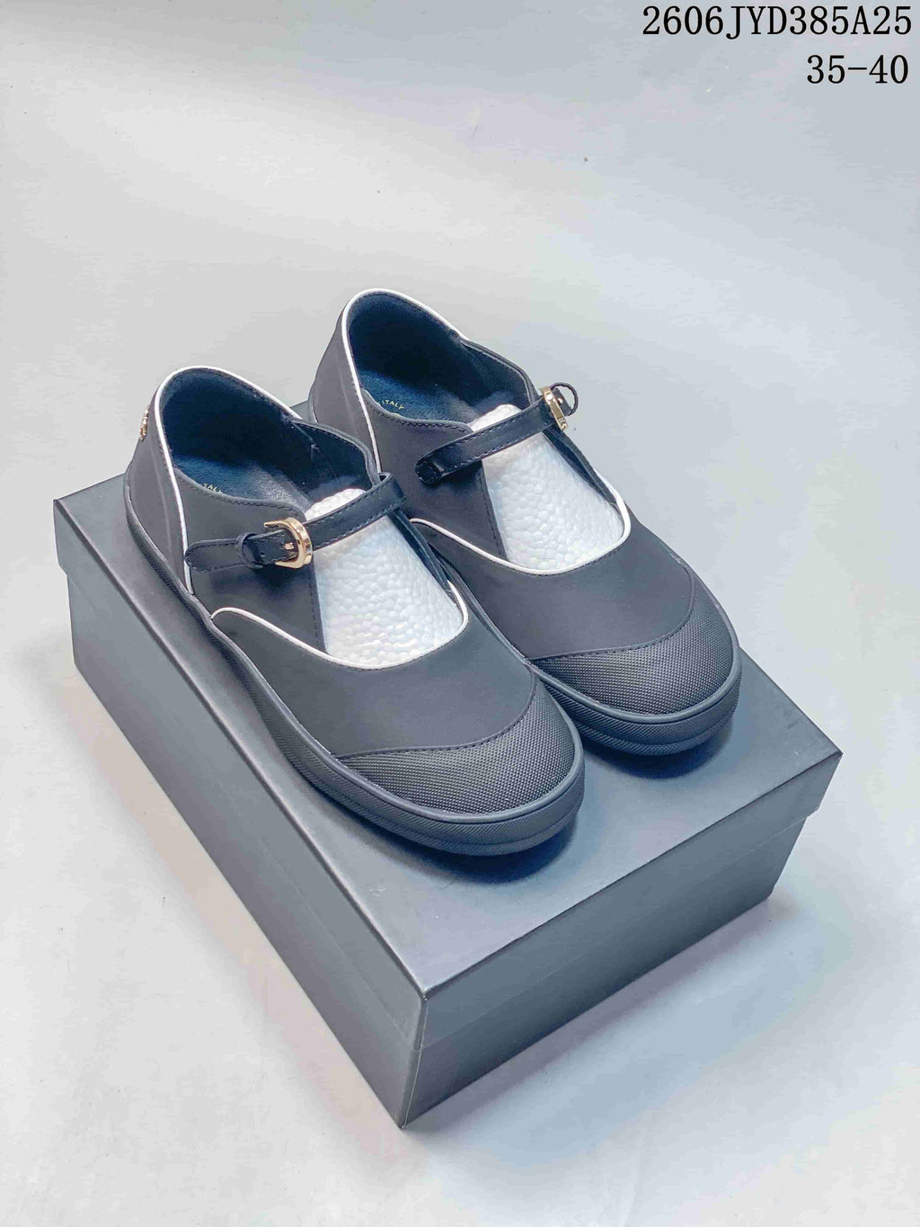 Charcoal Mary Jane flats with light trim and buckle straps, photographed as a pair.