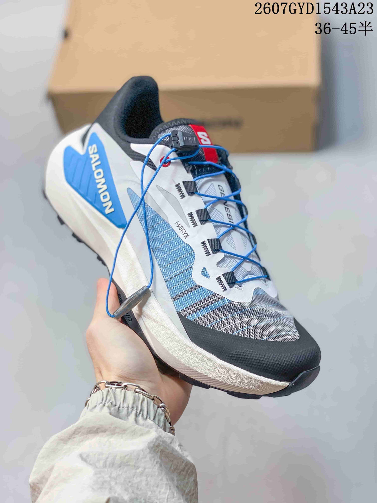 White and blue Salomon Genesis shoe with blue quick-lace cord and contrasting gray panels.