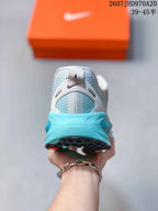 Rear view of a white and turquoise sneaker showing the padded collar, turquoise heel section, and black outsole.