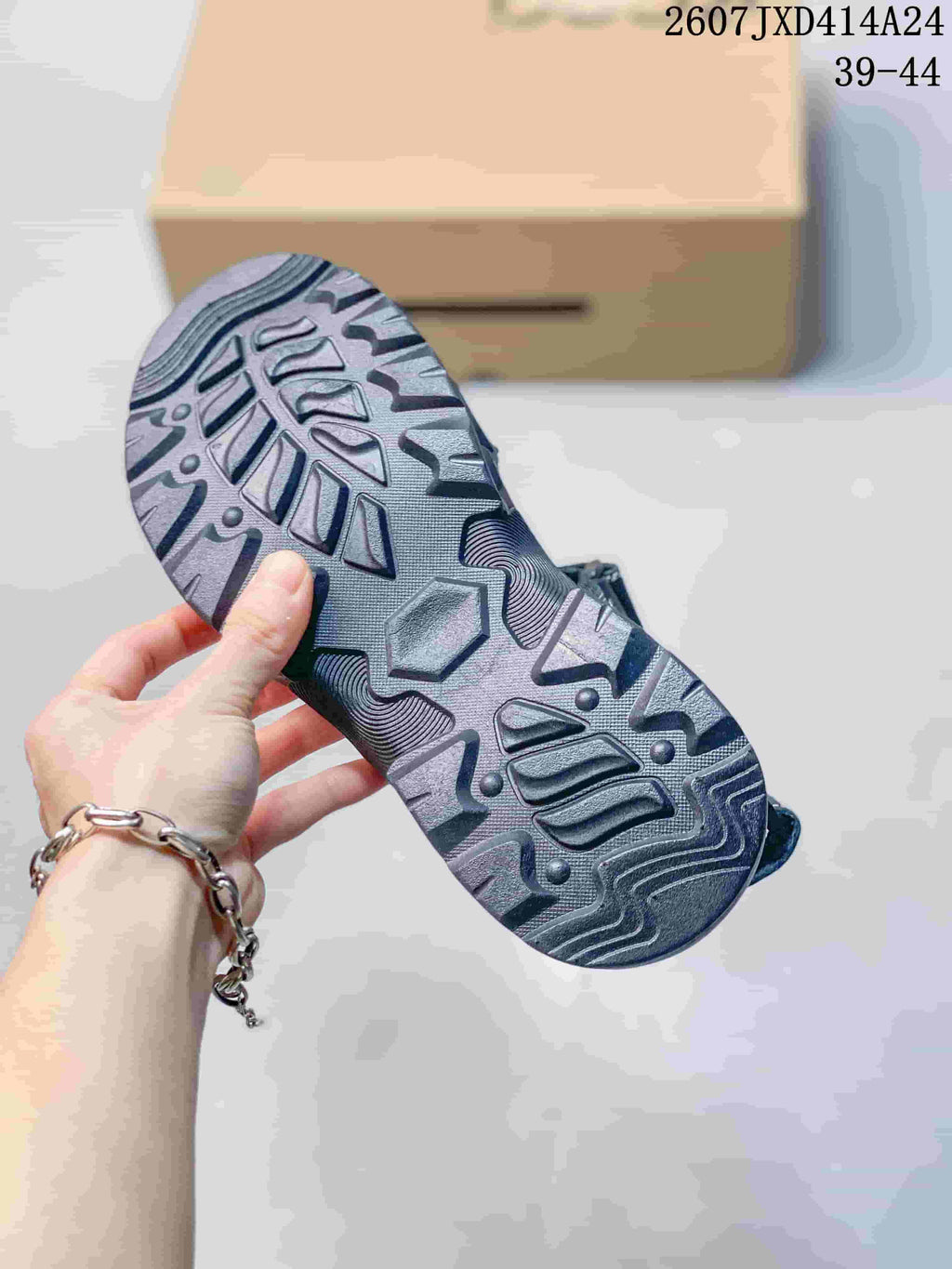 Close view of the patterned rubber outsole showing raised geometric tread on a dark black sandal.