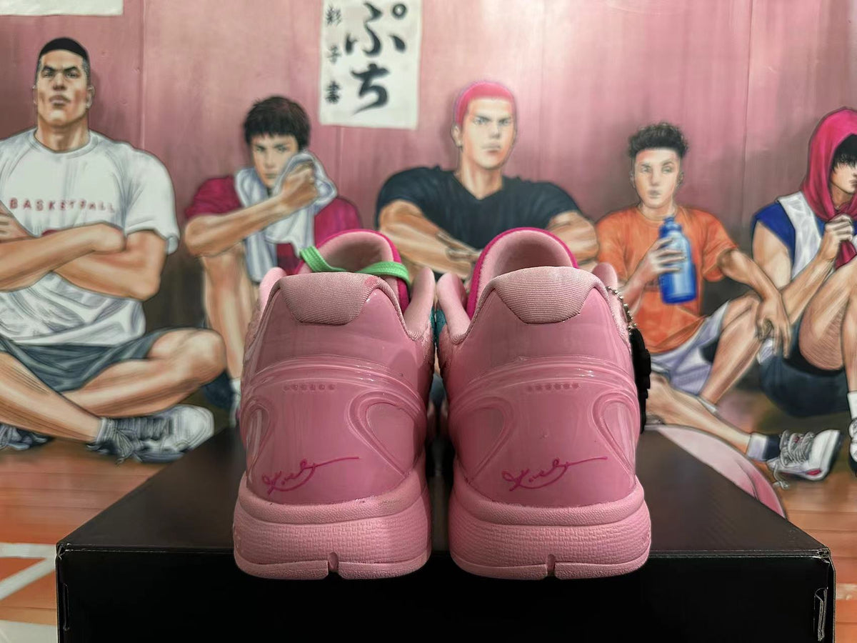Rear view of pink basketball shoes with green heel accents and signature-style heel markings.