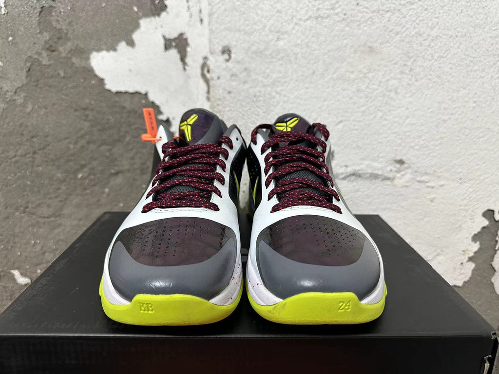 Front view of Nike basketball shoes with burgundy laces, dark toe panels, white uppers, and bright yellow-green accents.
