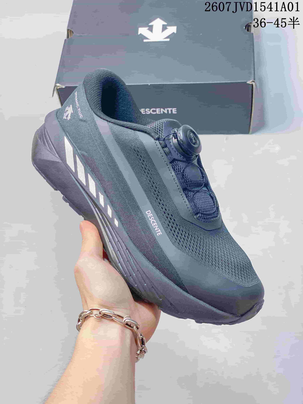 Side view of a dark gray Descente running shoe with a dial closure.