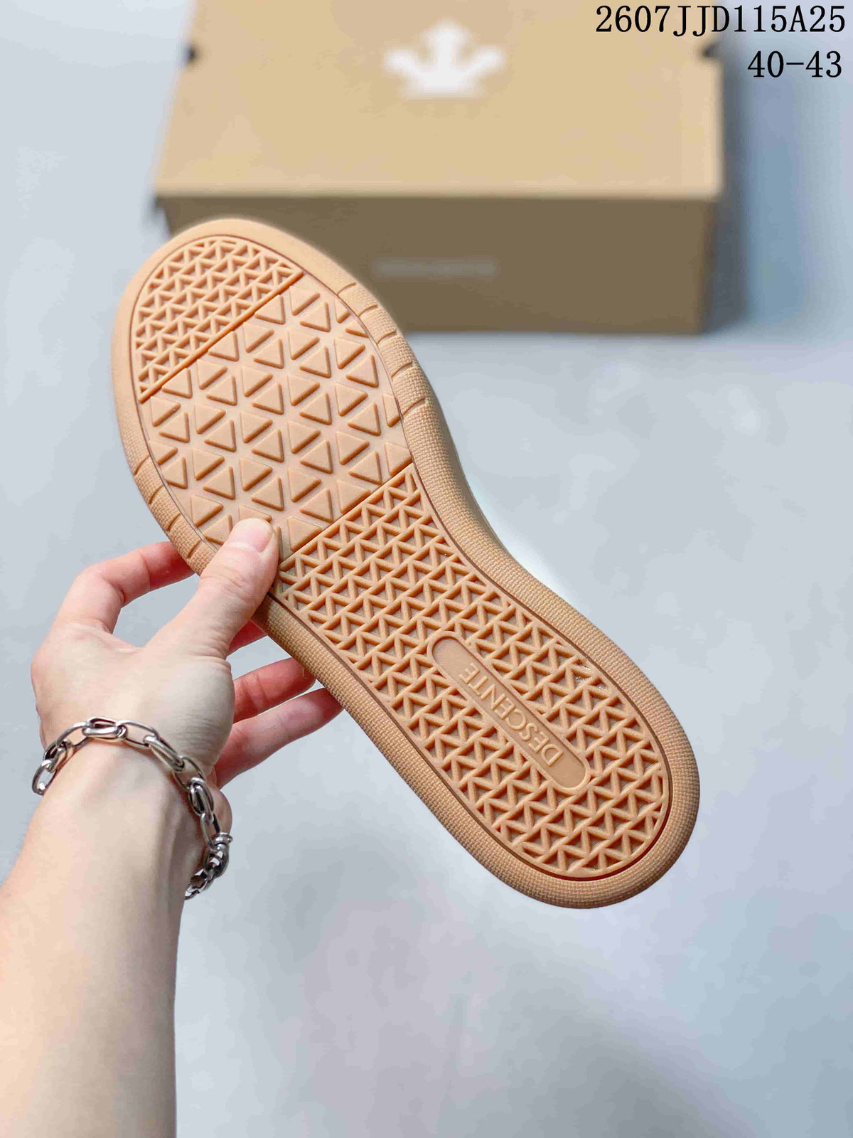 Close-up of the gum-colored outsole showing a geometric triangular tread pattern and DESCENTE branding.