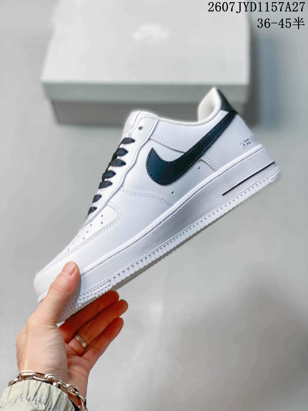 Side view of a white low-top sneaker with a black Swoosh, black outsole accent, and graphic heel detailing.