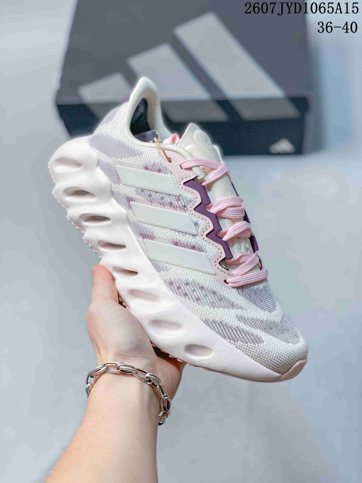 Angled side view of the white and pink sneaker showing the layered side panels and sculpted sole.