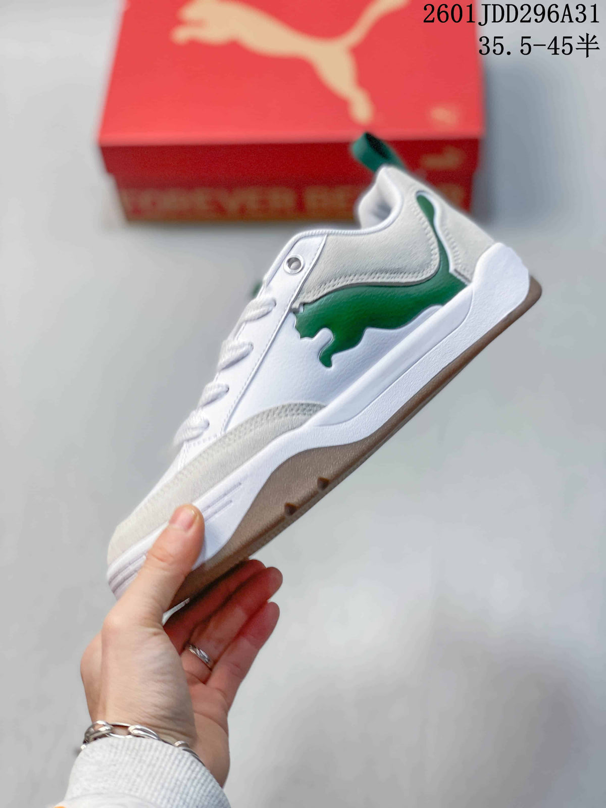 Side view of a white PUMA sneaker with a green side accent, white sole and brown-toned outsole.