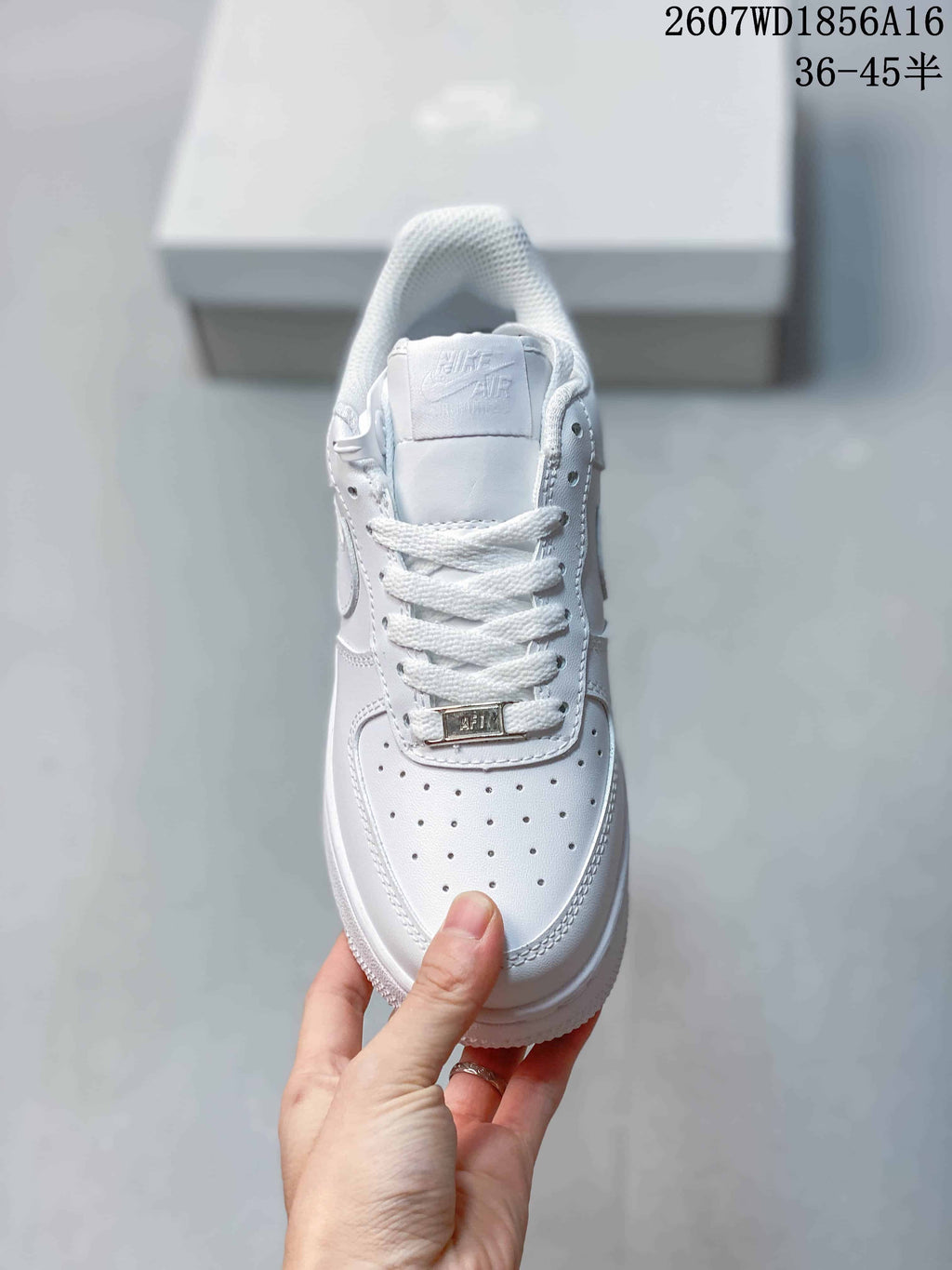 Top view of the white sneaker showing the perforated toe box, white laces, tongue, and metallic lace ornament.
