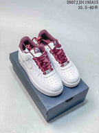 Pair of white Nike Air Force 1 low-top sneakers with burgundy laces and accents displayed on a shoebox.