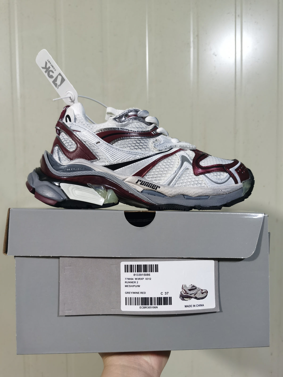 Puma Runner 2 sneaker displayed on its box; the label shows style code 779064 W3RX 0312, color Grey/Wine Red, and size C 37.