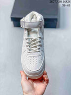 Front view of a white mid-top sneaker showing the lace-up closure, perforated toe box, padded collar, and ankle strap.