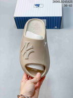 Top view of a beige MLB slide sandal showing the open toe, wide logo strap, and textured surface.