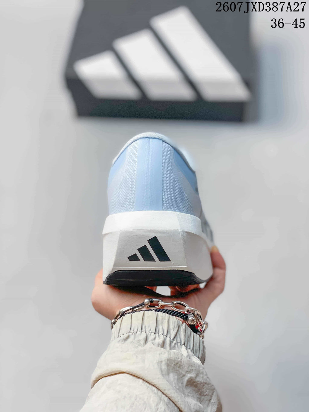Rear view of the light blue shoe showing the white heel section, adidas logo, and black outsole edge.
