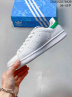 Side view showing the white upper, perforated panels and green heel accent