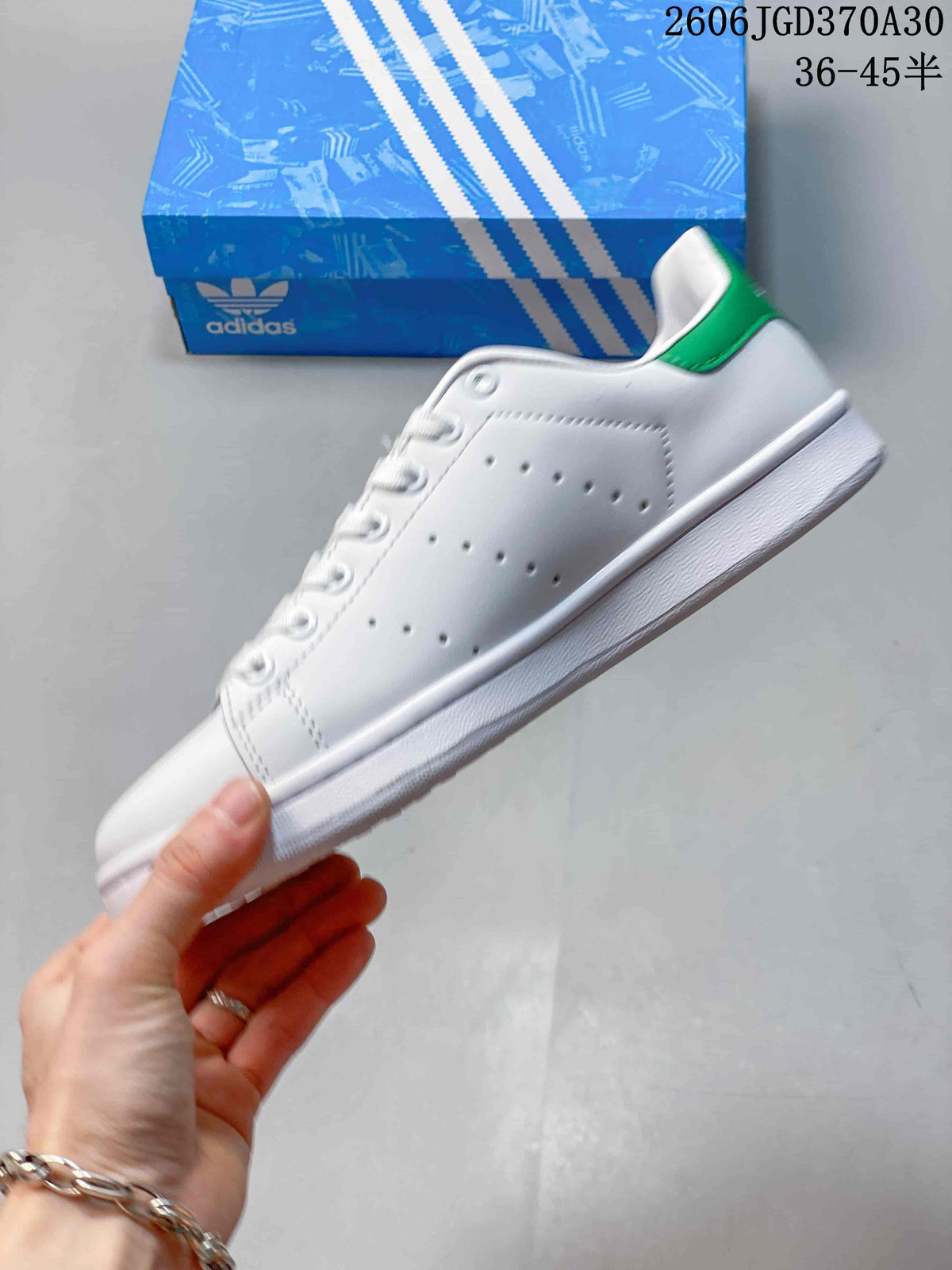 Side view showing the white upper, perforated panels and green heel accent