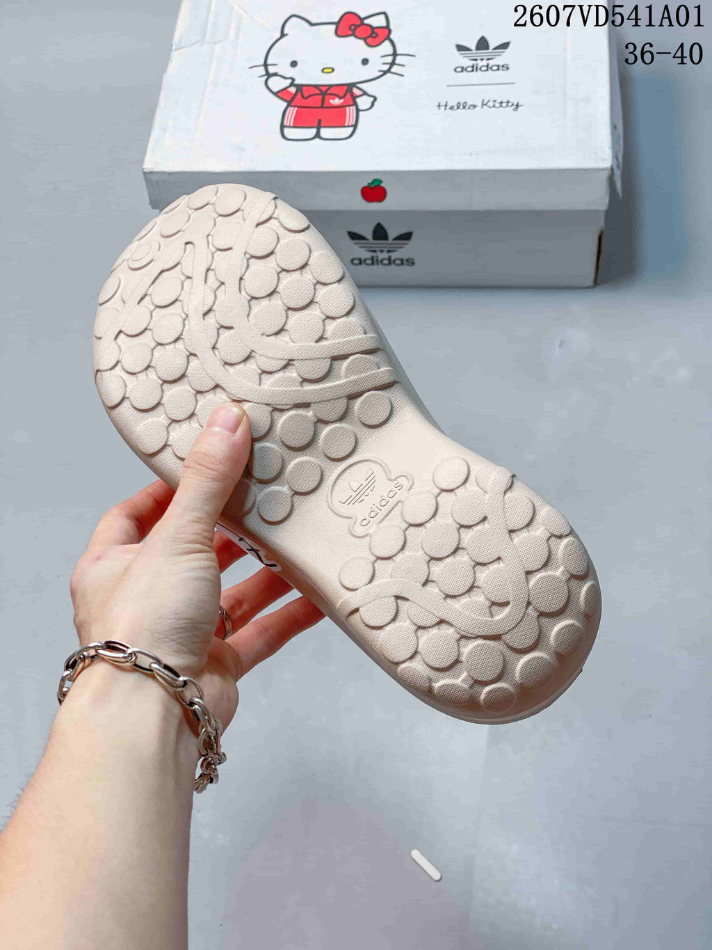 Textured outsole of the beige Hello Kitty mule clog beside its branded box